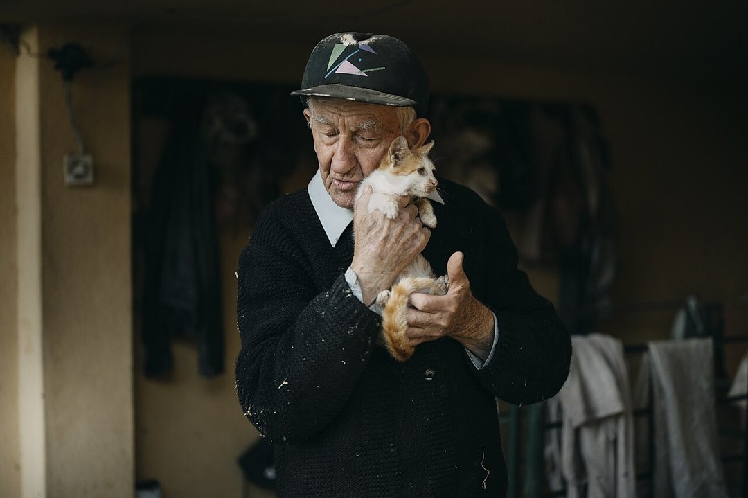 Pessoa idosa aposentada segurando um gatinho em casa
