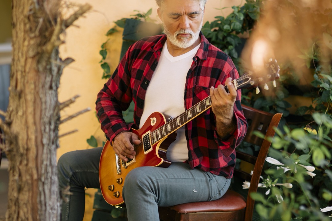 Senhor idoso toca violão em um jardim
